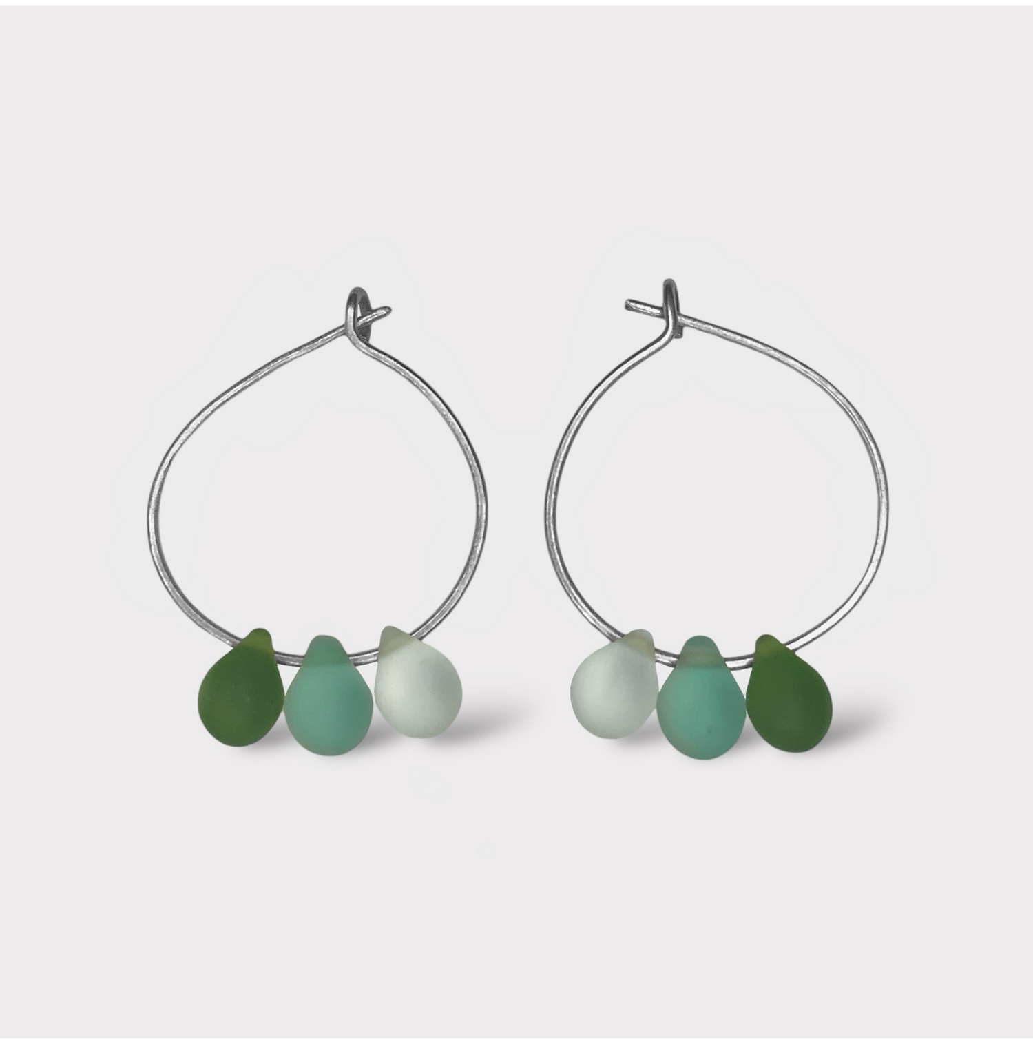 minimalist-small-hoop-earrings-with-matte-frosted-glass-teardrop-beads-in-pastel-colors-shot-against-a-flat-pink-background-jewelry-by-meow-iris-collection