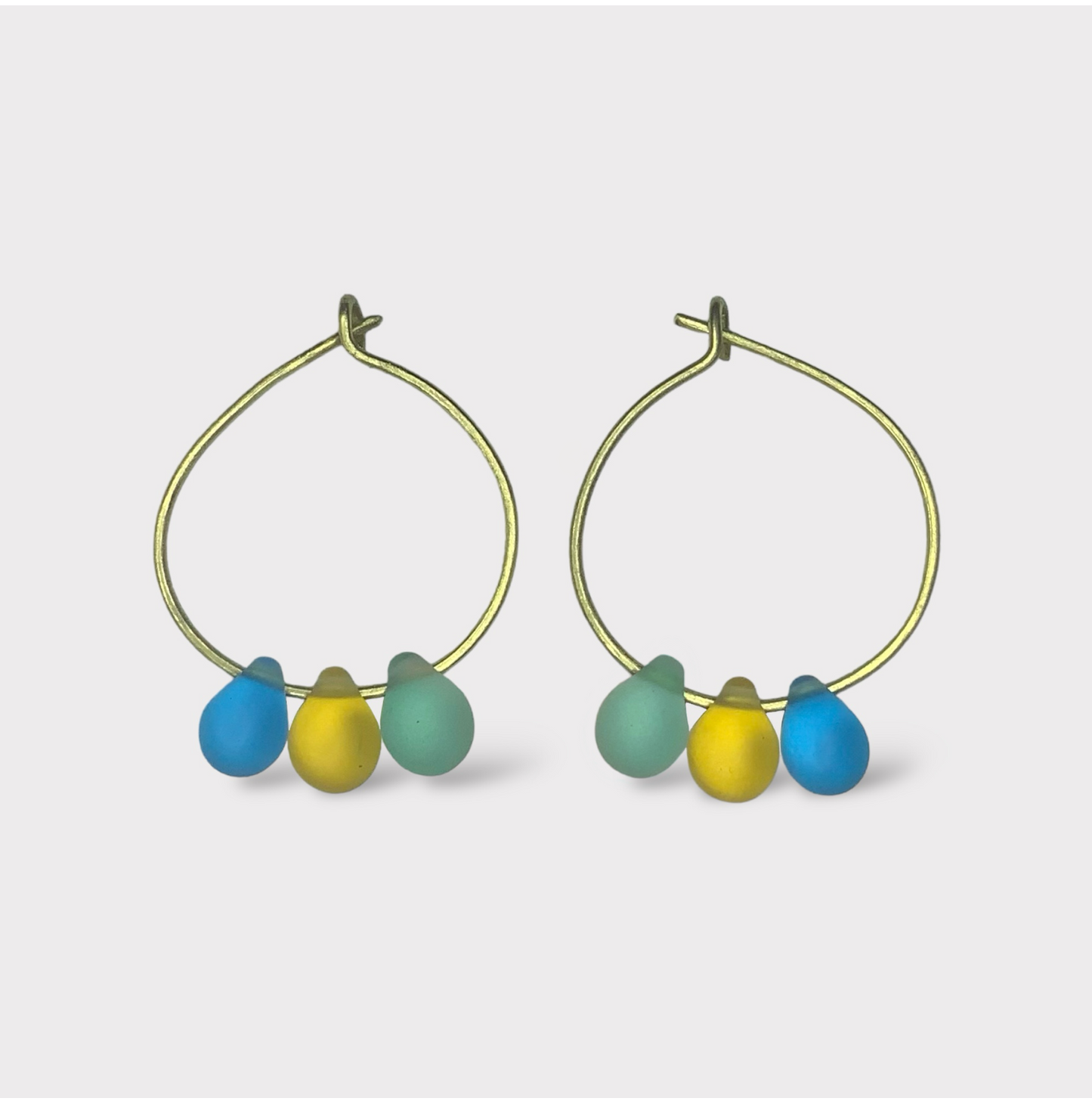 Bold gold hoop earrings featuring seaglass pendants in yellow, blue, and green. A vibrant and lively design inspired by the mythical ambrosia of Greek summers.