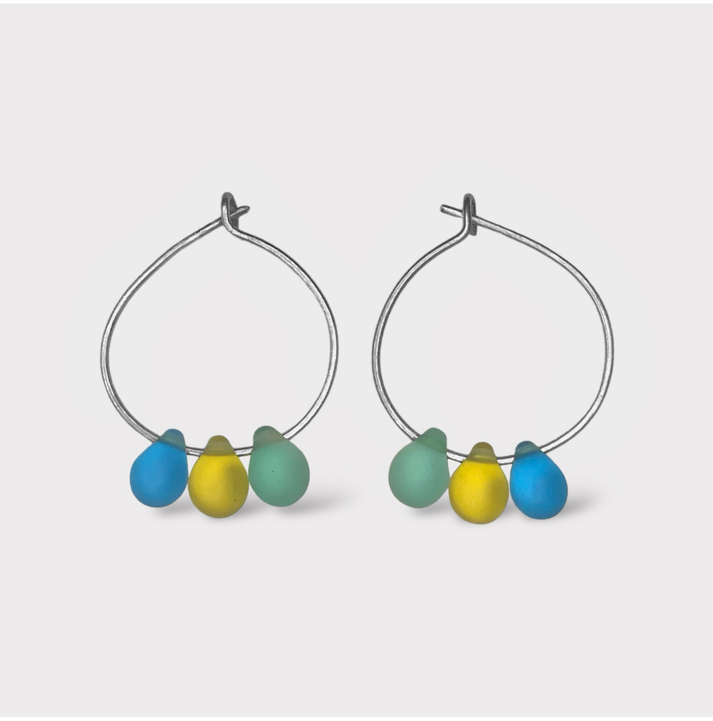 Vibrant silver hoop earrings with seaglass pendants in yellow, blue, and green tones. A bold and cheerful design inspired by the mythical ambrosia of Greek summers.