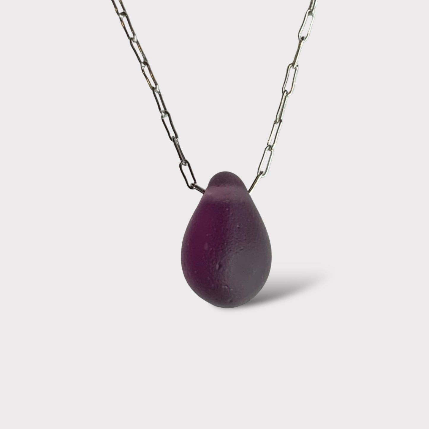 A rich berry matte teardrop-shaped glass pendant, suspended on a stainless steel chain, styled on a clean white background for a bold and elegant look.