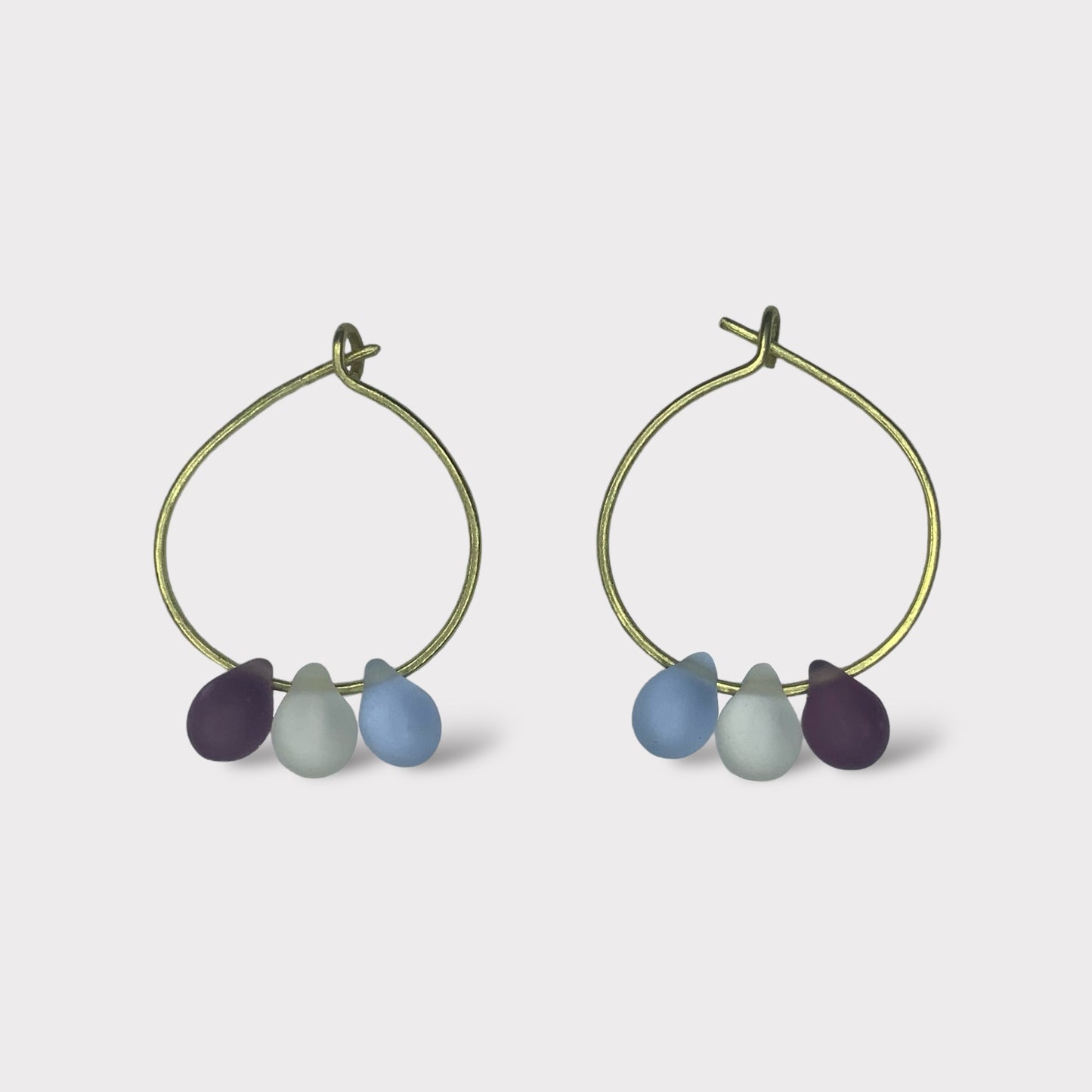 Elegant gold hoop earrings with smooth seaglass charms in rich blueberry purple, icy blue, and deep teal hues. Perfect for adding a cool, refreshing touch to your summer outfits.