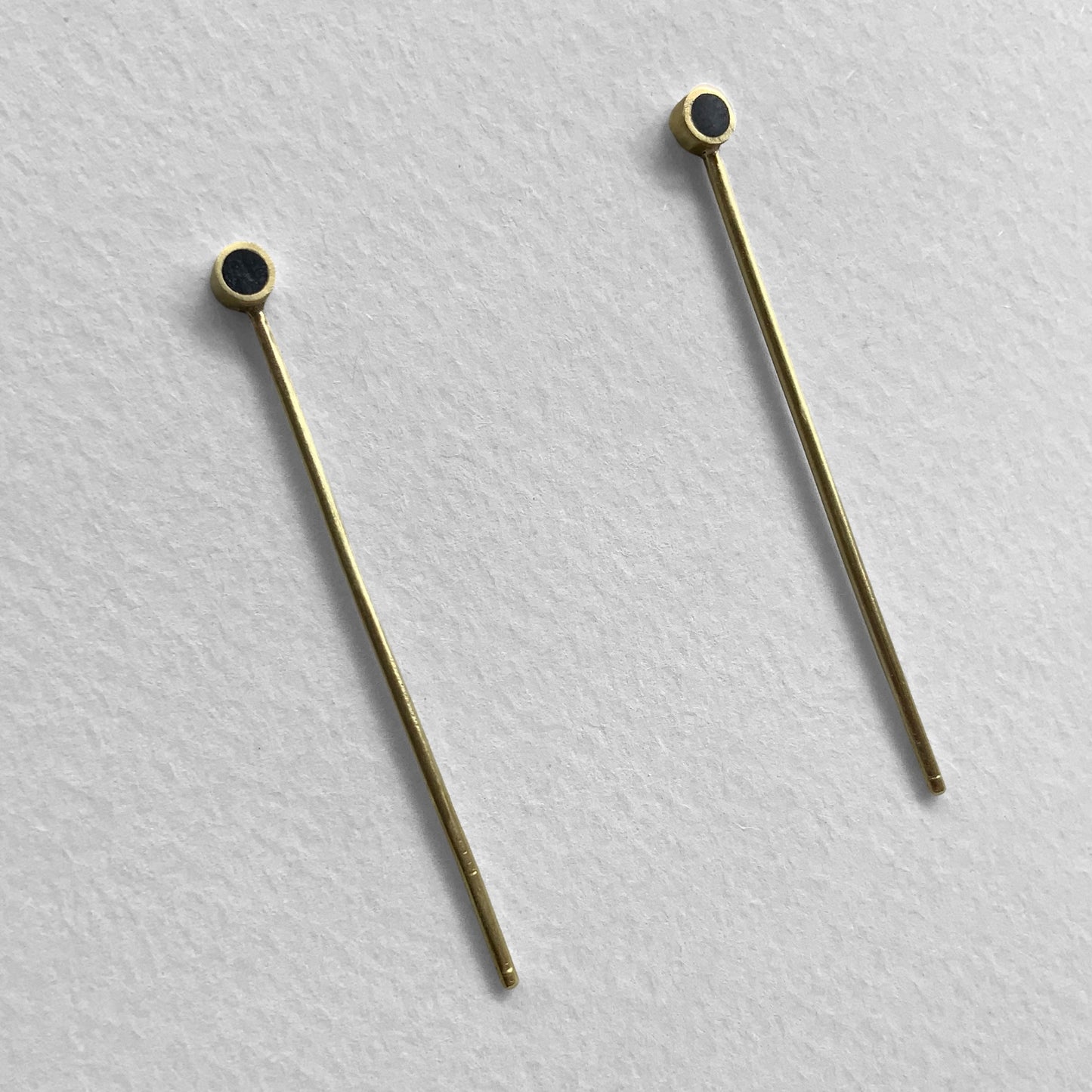 Elegant gold earrings with a sleek long bar and black circular details, handcrafted for a modern and minimalist look.