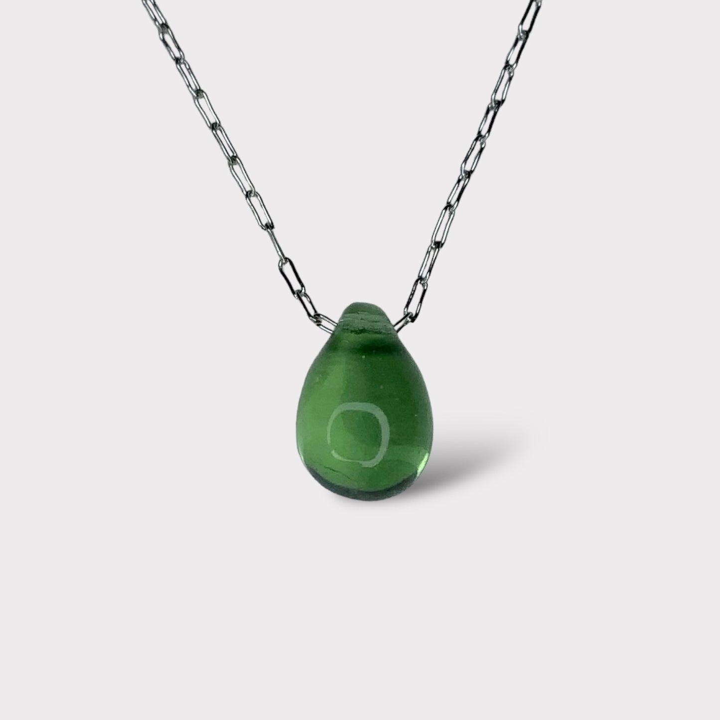 A vibrant green translucent teardrop-shaped glass pendant, suspended on a stainless steel chain, styled on a clean white background for a fresh and modern look.