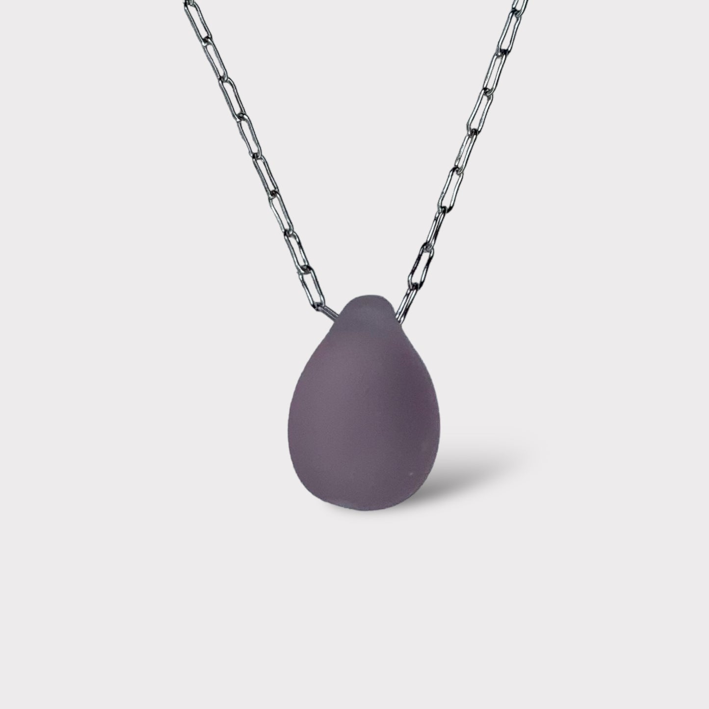 A soft lilac matte teardrop-shaped glass pendant, hanging from a stainless steel chain, displayed on a white background for a delicate and modern design.
