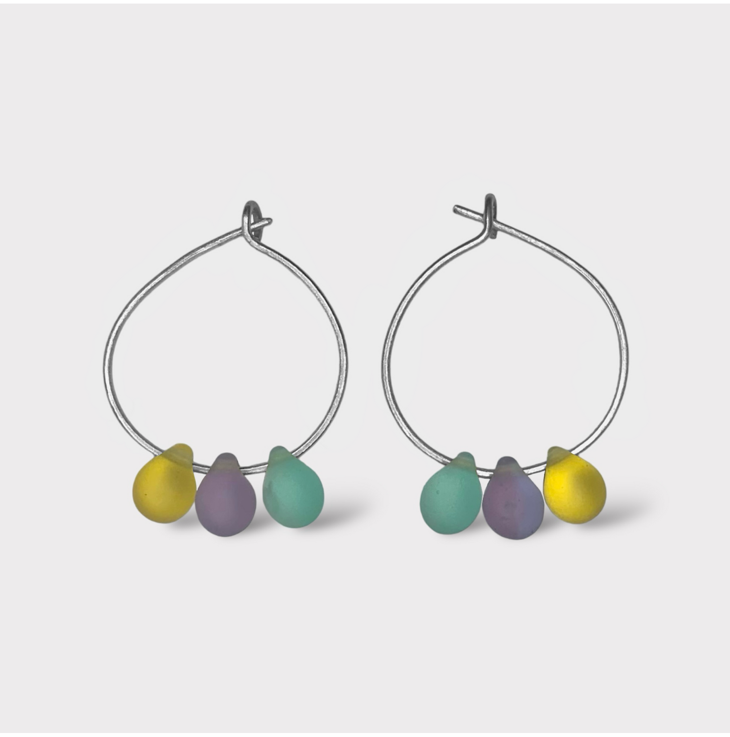 Minimalist silver hoop earrings featuring pastel seaglass drops in lavender, mint green, and sunny yellow. Inspired by the sweet and colorful world of French macarons.