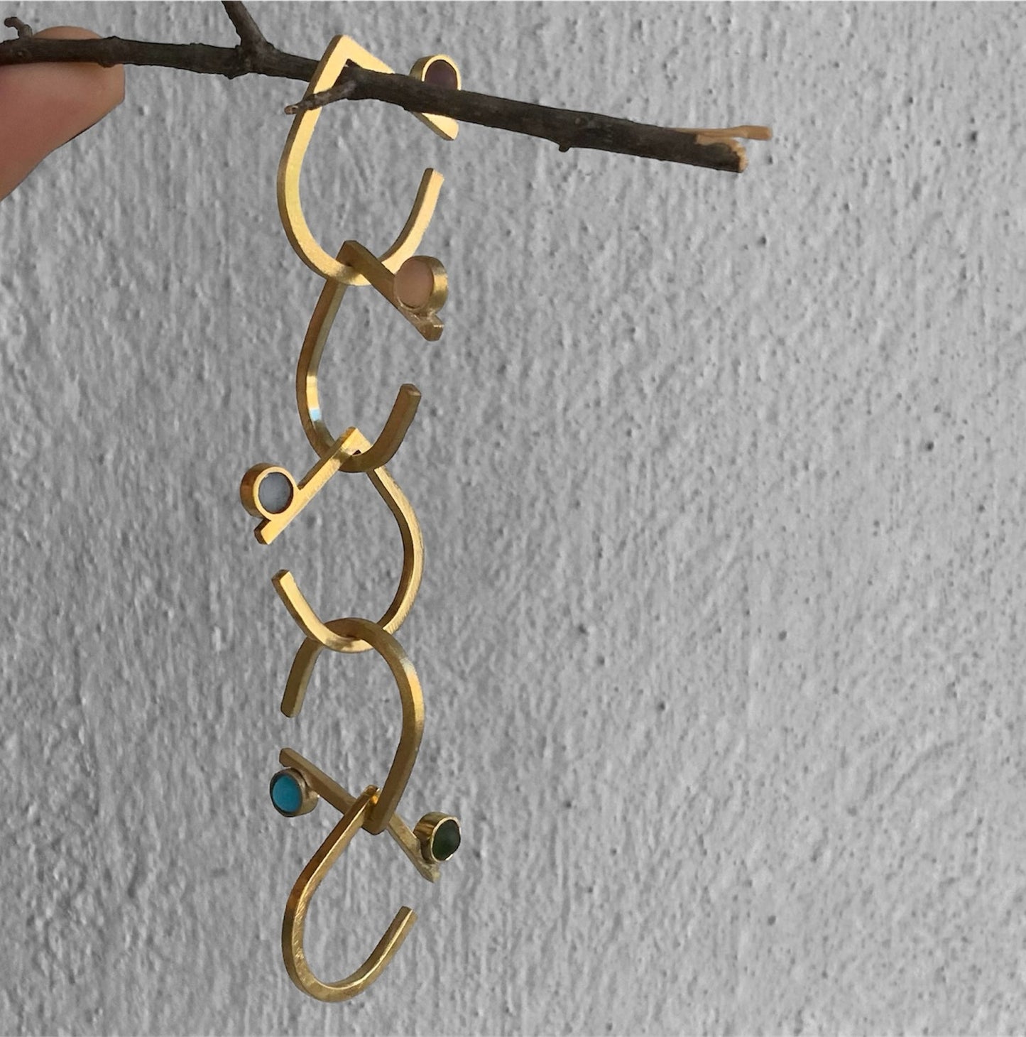 Unique handcrafted gold rings with frosted glass cabochons, arranged in a cascading style on a branch for a contemporary and organic display.