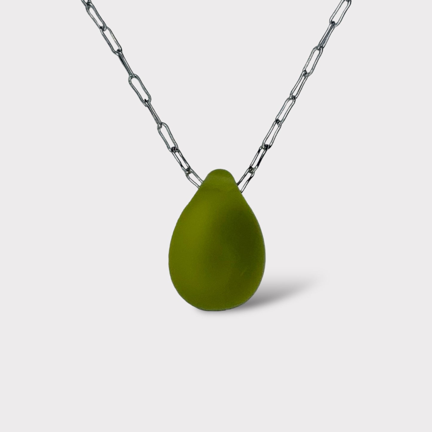 A minimalist necklace featuring a matte olive green teardrop-shaped glass pendant, elegantly suspended on a stainless steel chain, styled on a white background.