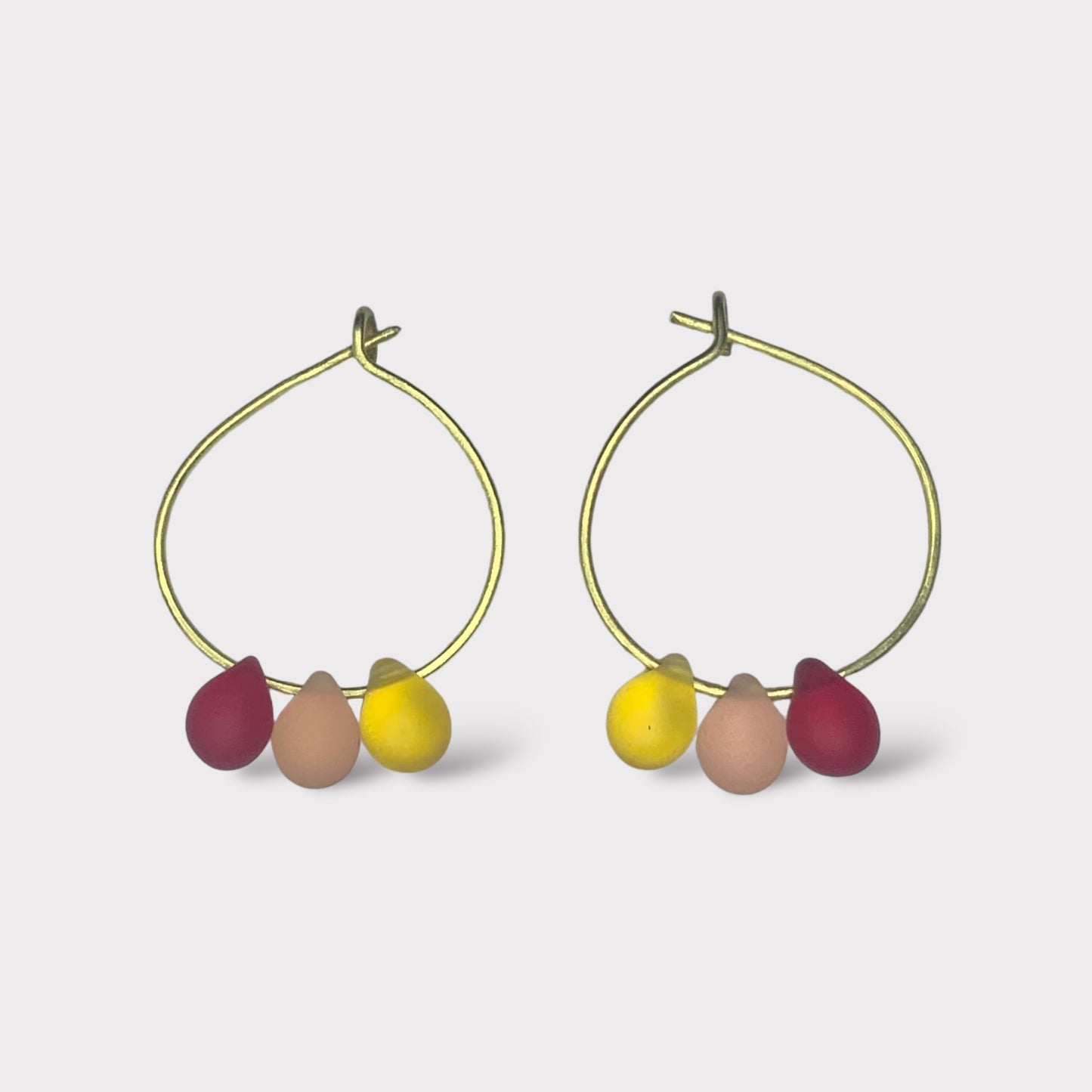 Bright and cheerful gold hoop earrings adorned with seaglass pendants in vibrant red, yellow, and orange. A fun and fruity design inspired by summer sorbets.