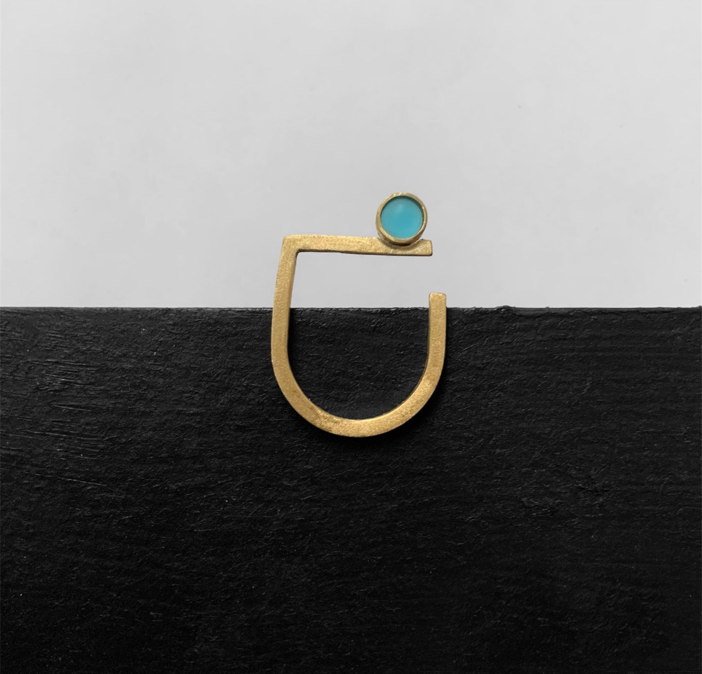 Minimalist gold ring with a frosted turquoise glass accent, handcrafted for an elegant and modern style on a black and white background.
