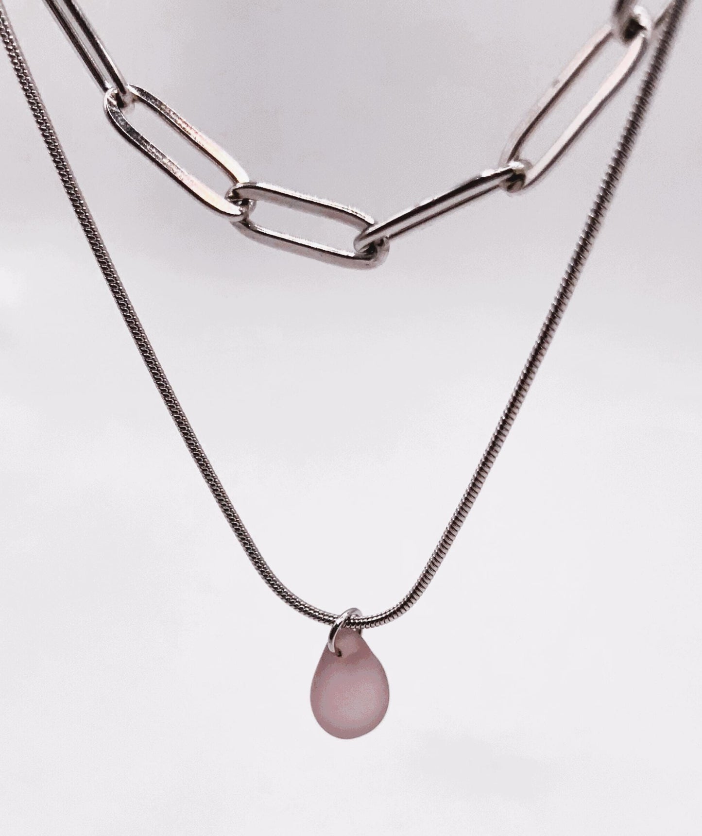 Close-up of a layered silver snake chain necklace featuring a pastel lavender frosted glass teardrop charm. A modern, handcrafted design for women who love understated elegance.