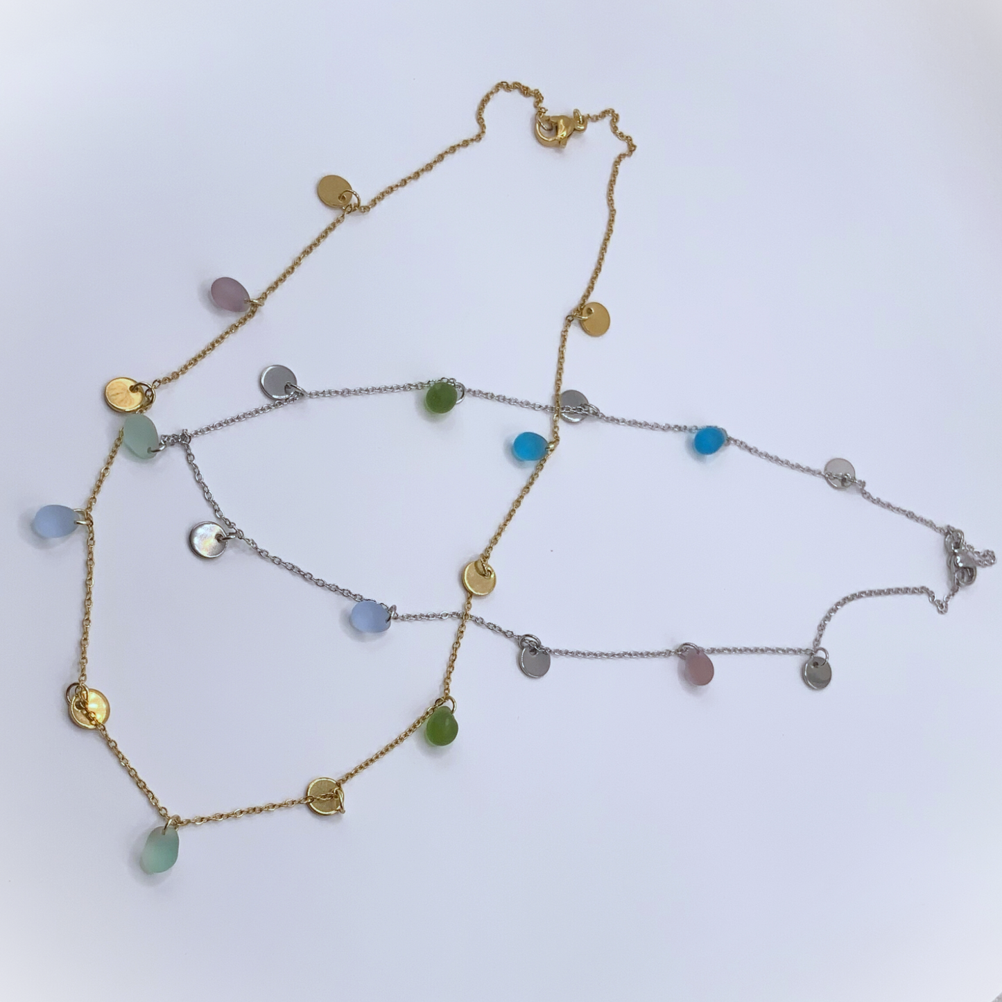 Gold and silver chain necklaces with frosted glass beads in soft pastel tones and coin charms, handcrafted in Greece. A minimalist design ideal for casual and formal outfits.