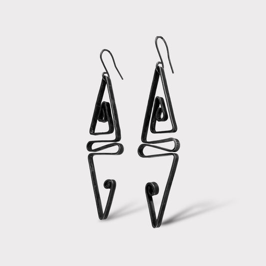 A pair of handcrafted abstract geometric earrings with a bold black finish, featuring angular and spiral designs, suspended on black hooks, styled on a white background for a striking and modern look.