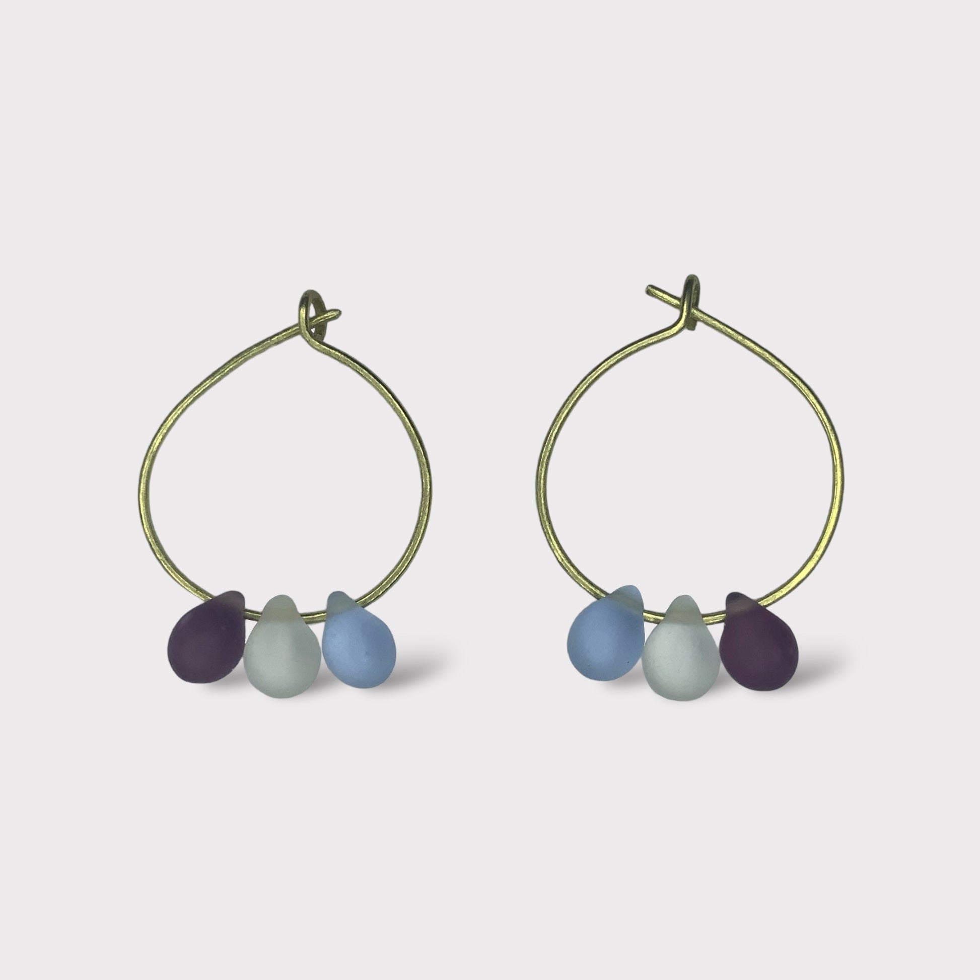 Elegant gold hoop earrings with smooth seaglass charms in rich blueberry purple, icy blue, and deep teal hues. Perfect for adding a cool, refreshing touch to your summer outfits.