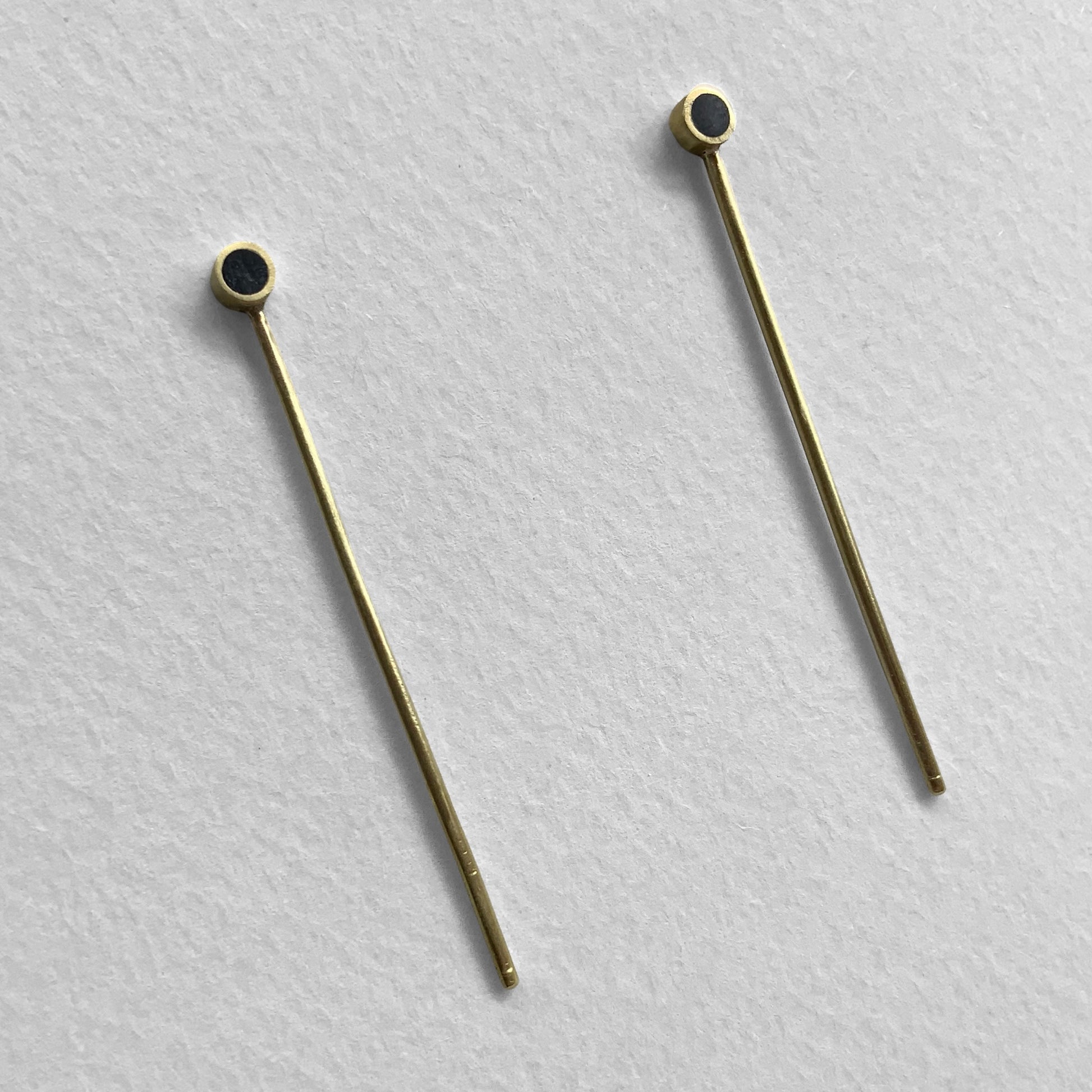 Elegant gold earrings with a sleek long bar and black circular details, handcrafted for a modern and minimalist look.