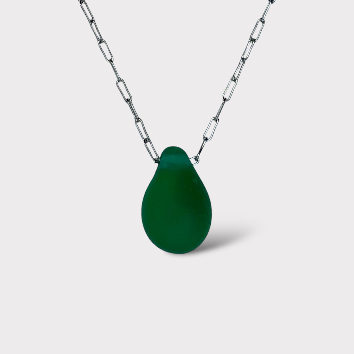 A deep emerald green matte teardrop-shaped glass pendant, suspended on a stainless steel chain, displayed on a white background for a bold statement.