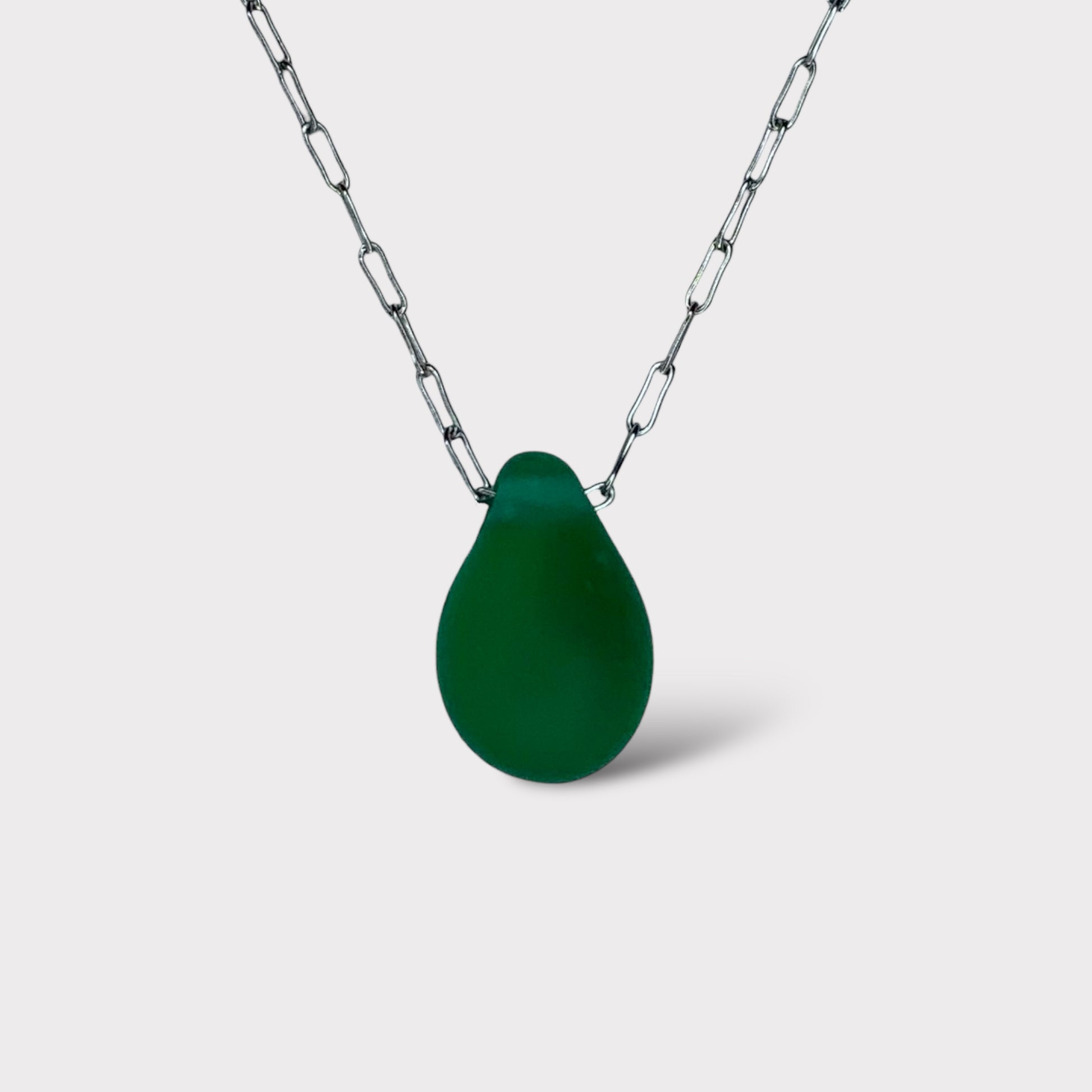 A deep emerald green matte teardrop-shaped glass pendant, suspended on a stainless steel chain, displayed on a white background for a bold statement.