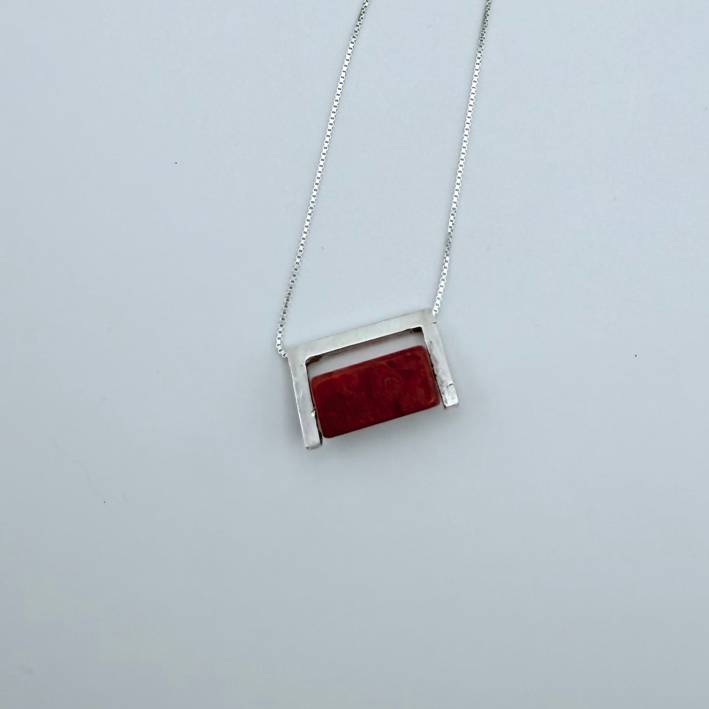 Full view of the Geometric Sterling Silver & Coral Necklace with a rectangular red coral block set in a sterling silver frame on a white background