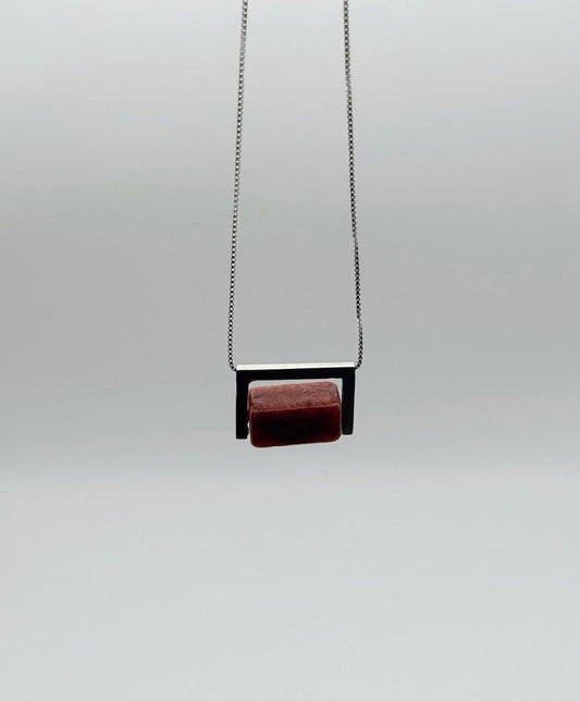 Hanging front view of the Geometric Sterling Silver & Coral Necklace with a red coral block set in a structured sterling silver frame on a white background