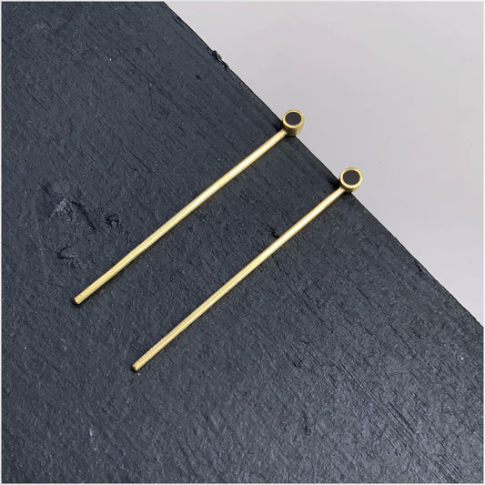 Minimalist gold earrings with black circular accents and long bar design, perfect for a sleek and modern style.