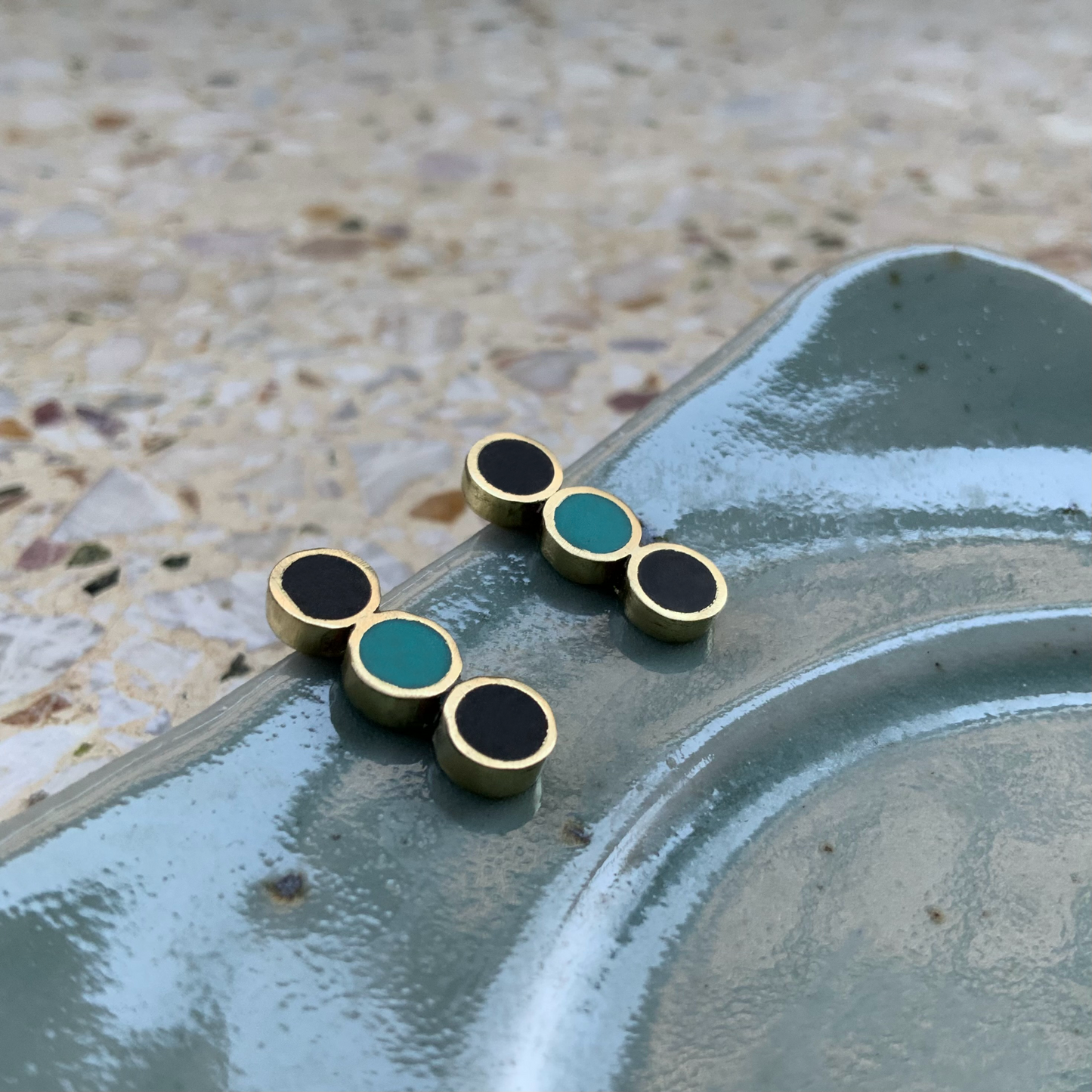 closeup-handmade-artisan-greek-medium-minimalist-stud-earrings-with-three-circle-shapes-with-black-and-turqoise-poymer-clay-inlay-on-reflective-pottery-jewelry-by-meow-dusk-and-dawn-collection-focal-studs