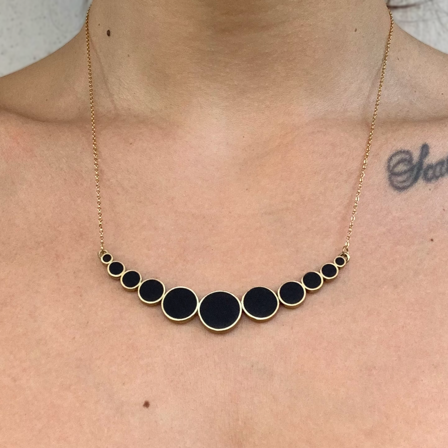 woman-neckline-wearing-handmade-artisan-greek-crescent-cascade-necklace-with-circular-minimalist-shapes-with-black-polymer-clay-inlay-jewelry-by-meow-dusk-and-dawn-collection