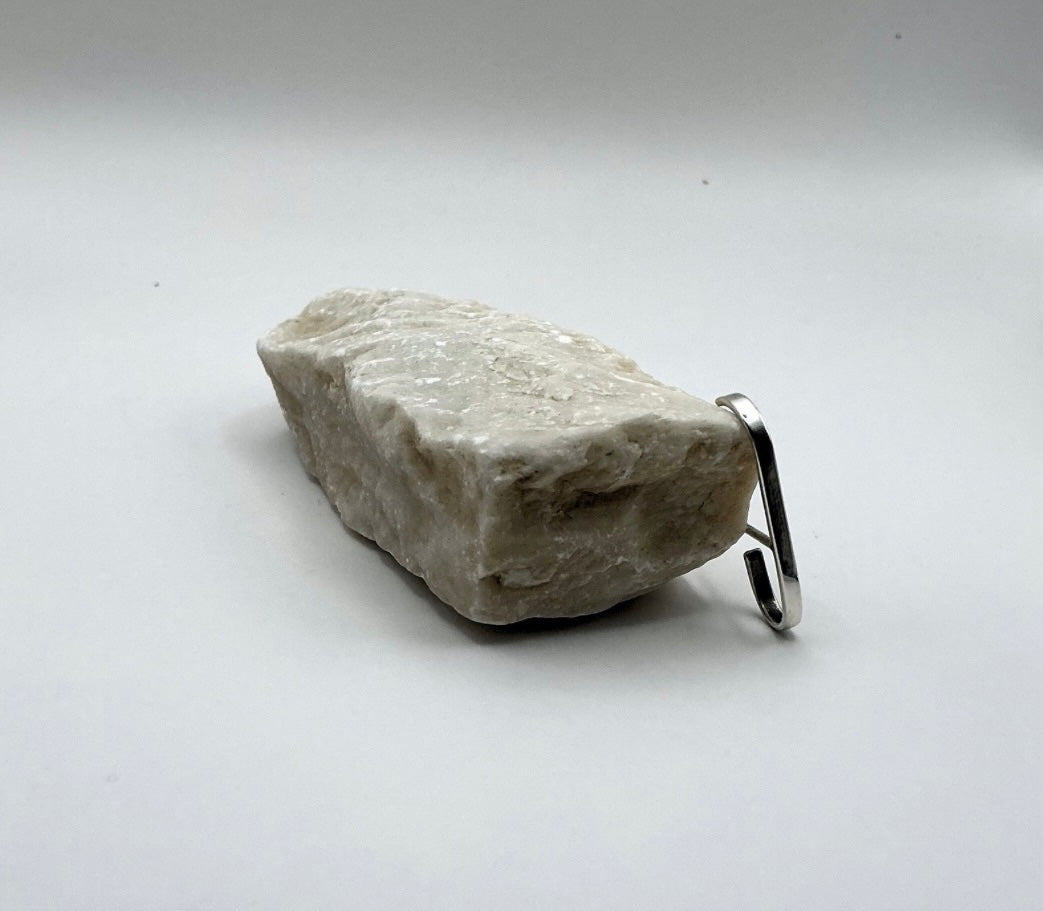 Angled view of the Minimalist Curve Sterling Silver Ear Hook displayed beside a light stone on a white background