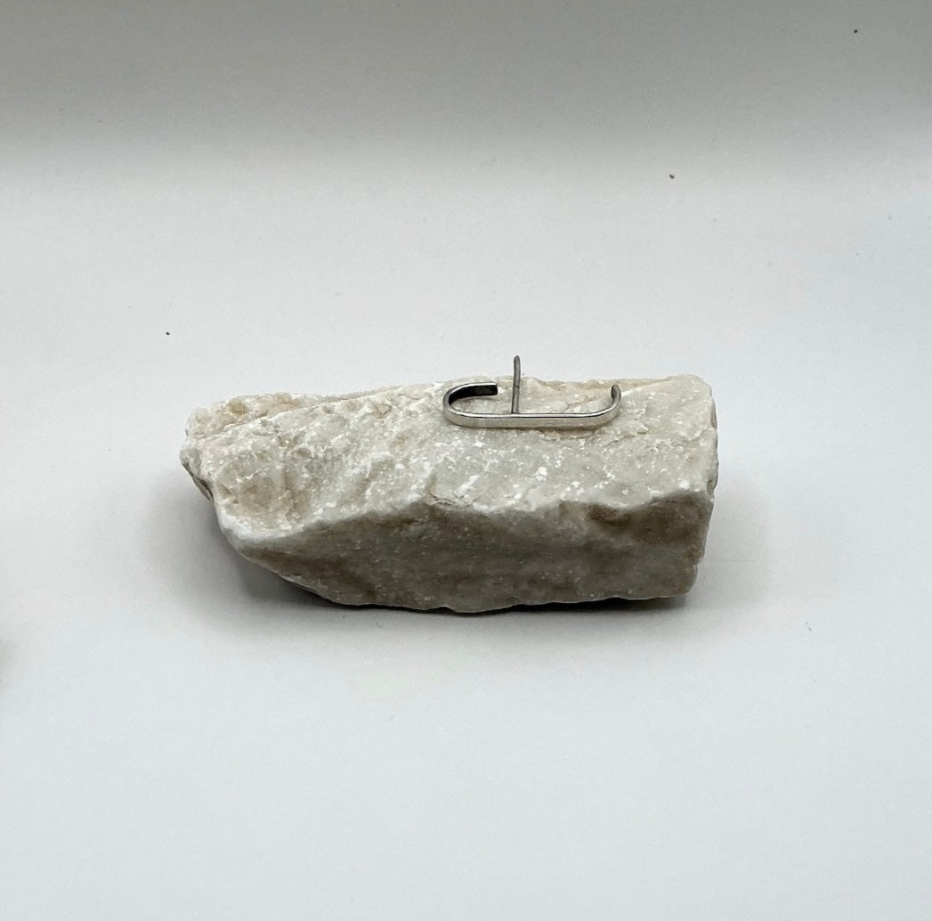 Full view of the Minimalist Curve Sterling Silver Ear Hook resting on a light stone background