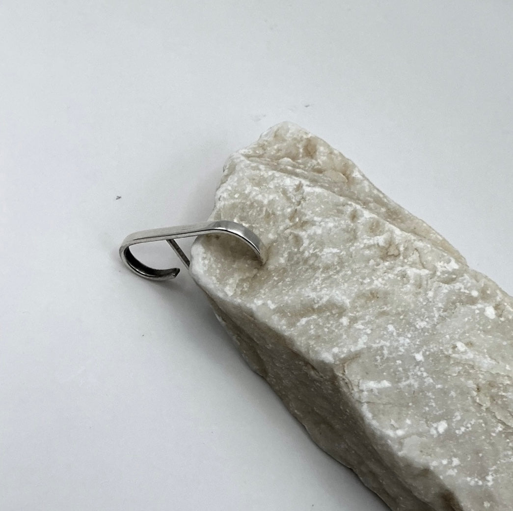 Minimalist Curve Sterling Silver Ear Hook leaning on a light marble stone on a light gray background