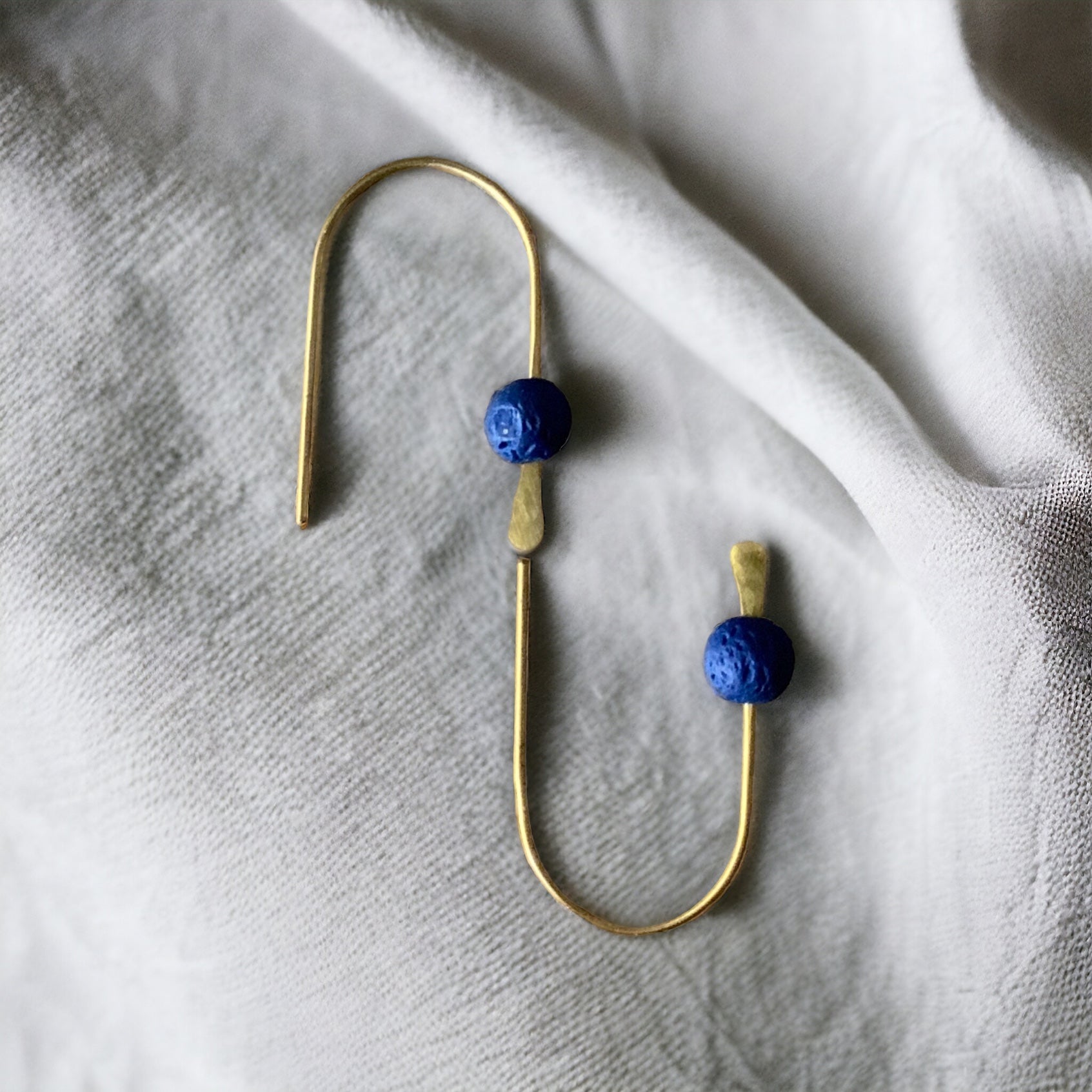 minimalist-arc-line-earrings-with-blue-lava-stone-jewelry-by-meow-minimalist-collection-on-white-fabric-product-photography