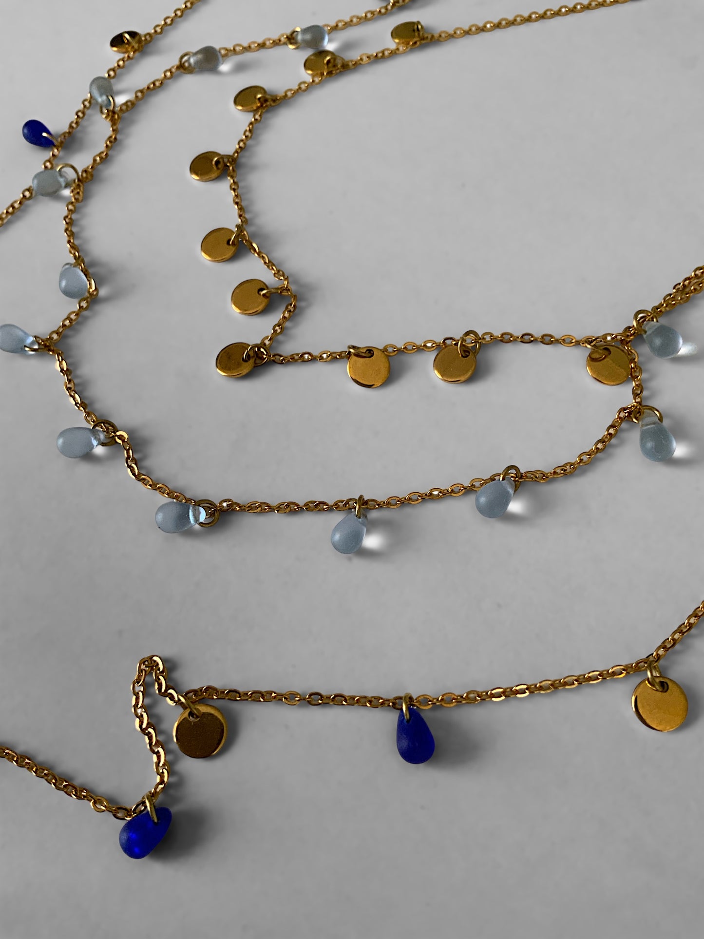 long-layered-boho-gold-chain-necklace-with-royal-and-sky-blue-sea-glass-beads-and-golden-pendant-coin-charms--jewelry-by-meow-iris-necklaces-boho-necklaces-layered-sea-glass-charm-necklace-closeup-top-right-angle