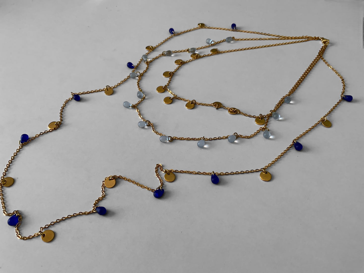 long-layered-boho-gold-chain-necklace-with-royal-and-sky-blue-sea-glass-beads-and-golden-pendant-coin-charms--jewelry-by-meow-iris-necklaces-boho-necklaces-layered-sea-glass-charm-necklace-full-product-photography