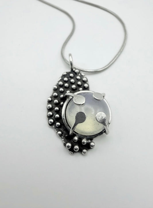 Silver pendant necklace with moonstone on a light gray background