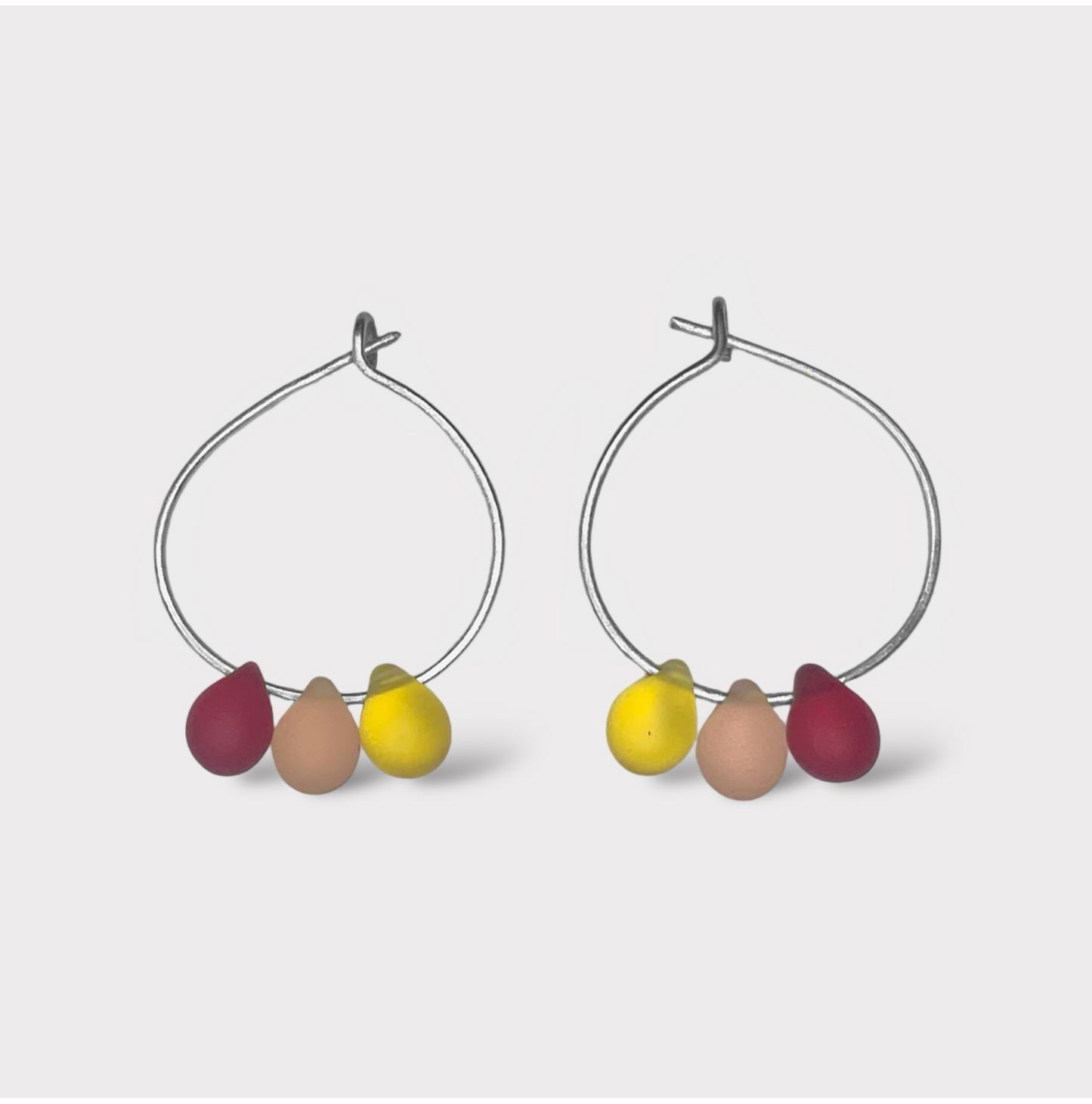 Colorful silver hoop earrings featuring seaglass pendants in red, yellow, and orange hues. A vibrant and fun design inspired by fruity summer sorbets.