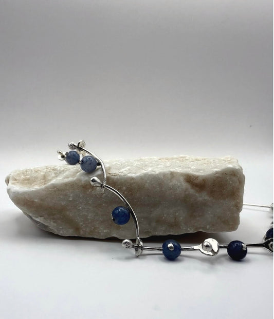 Handmade sterling silver necklace featuring hammered details and blue aventurine beads, inspired by sea waves, displayed on a stone.