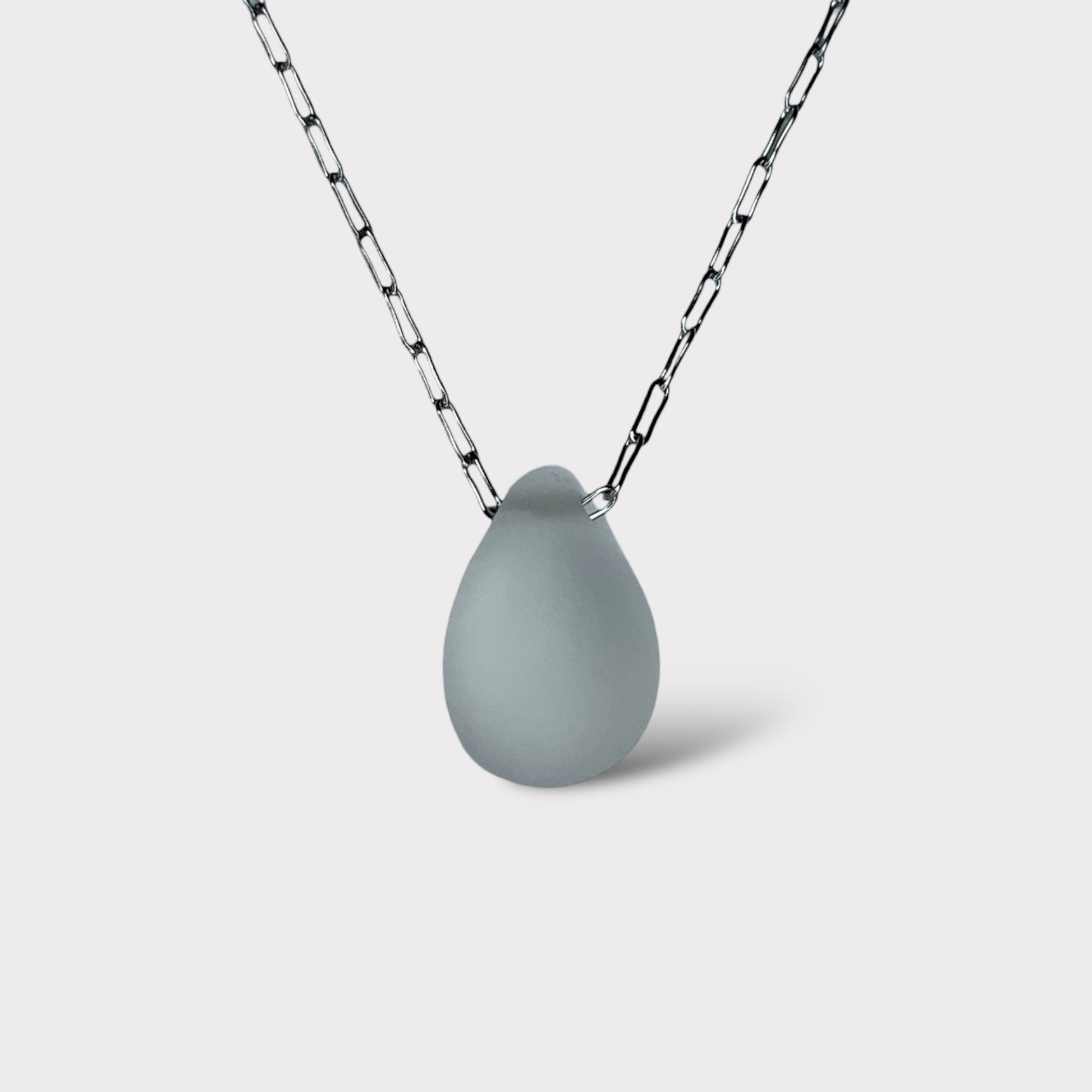 A frosted white matte teardrop-shaped glass pendant, elegantly suspended on a stainless steel chain, styled on a clean white background for a minimalist look.