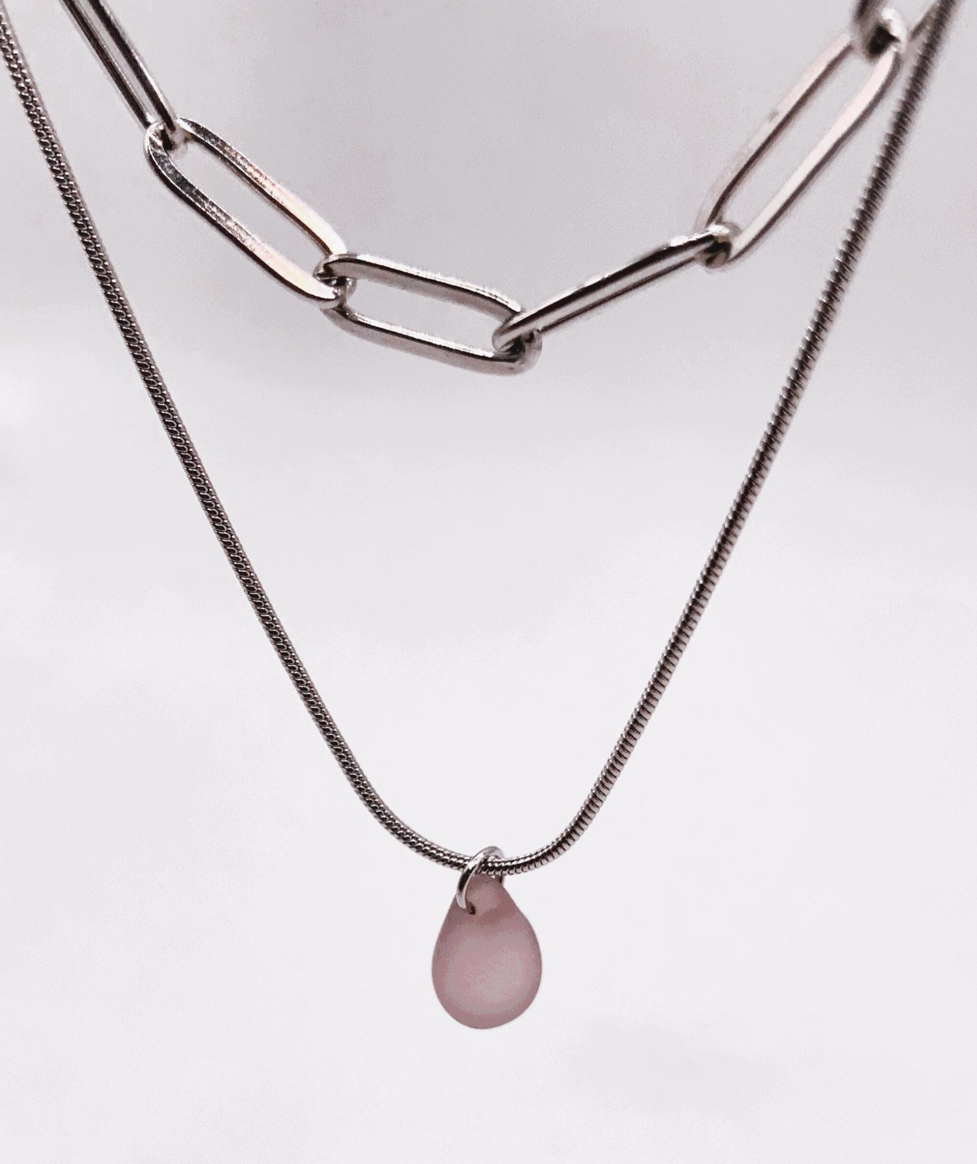 Close-up of a layered silver snake chain necklace featuring a pastel lavender frosted glass teardrop charm. A modern, handcrafted design for women who love understated elegance.