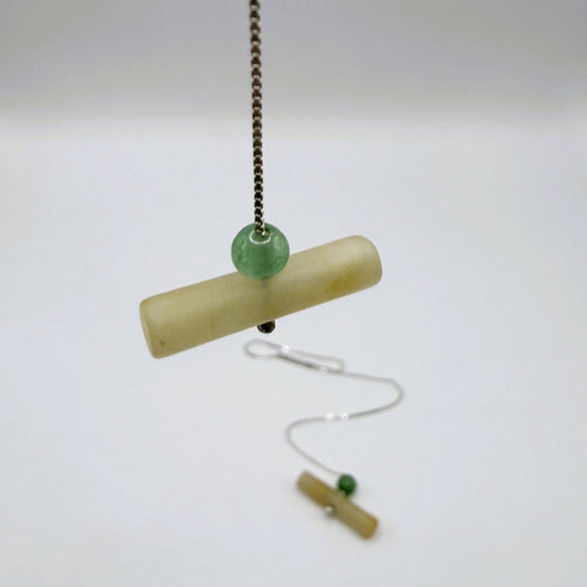 Minimalist sterling silver threader earring with jadeite cylinder and green aventurine bead, hanging on a white background