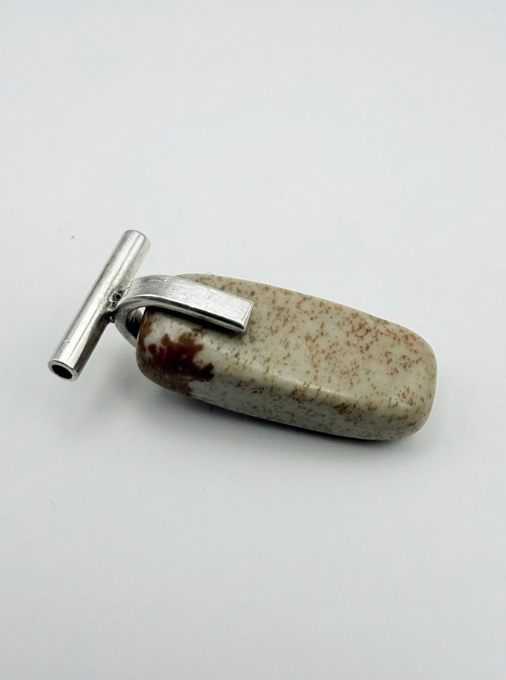 Close-up of the landscape jasper stone pendant with sterling silver T-bar detail on a light gray background