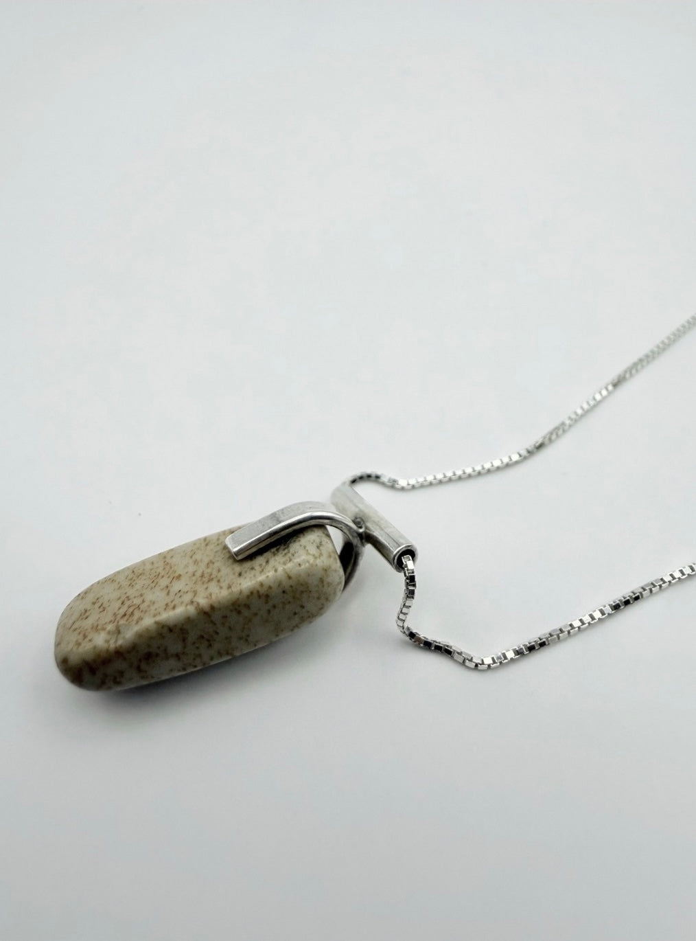 Sterling silver landscape jasper necklace shown on the side with box chain and stone pendant on a light gray background