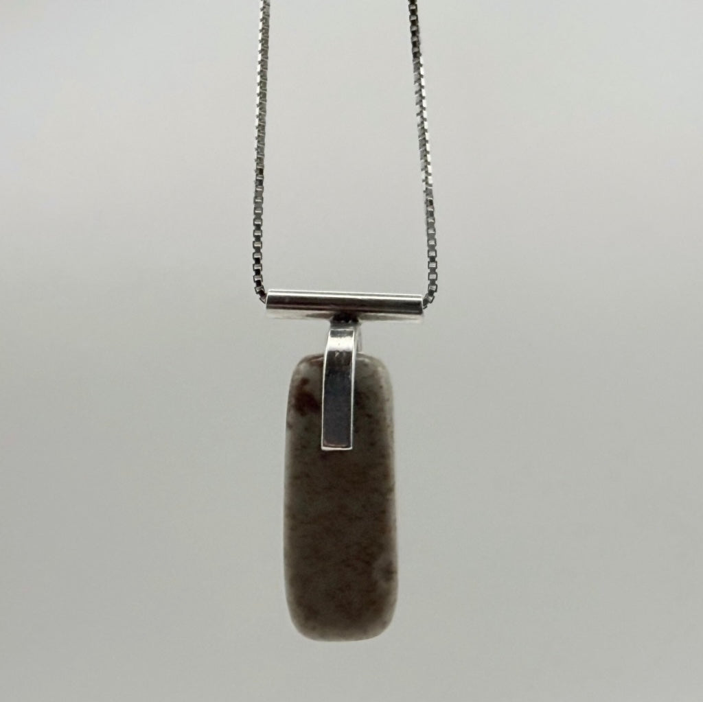Vertical front view of the landscape jasper stone pendant with sterling silver T-bar detail on a light gray background