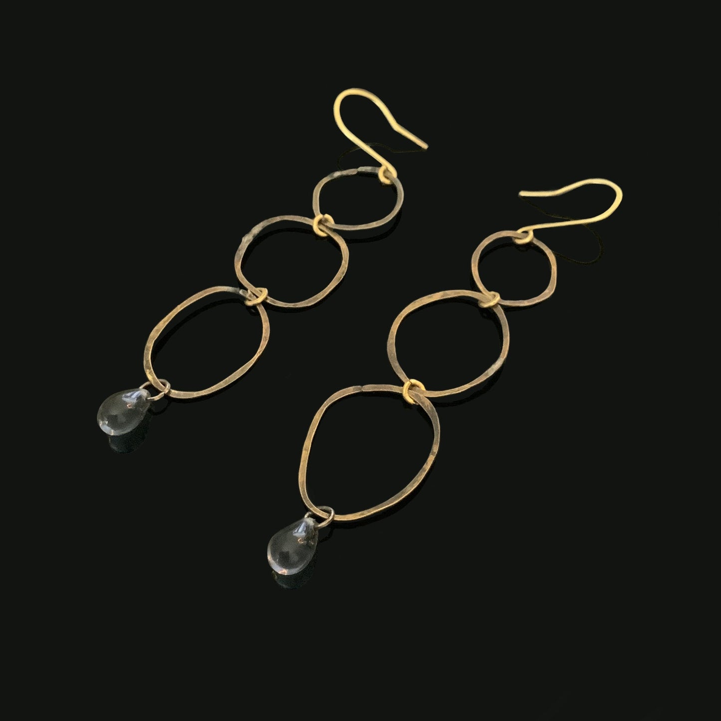 Simple-modern-long-oxidized-brass-earrings-three-circle-links-with-montana-blue-glass-teardrop-bead-at- the-bottom-black-reflective-background-product-photo-jewelry-by-meow-iris-collection-maeve-earrings